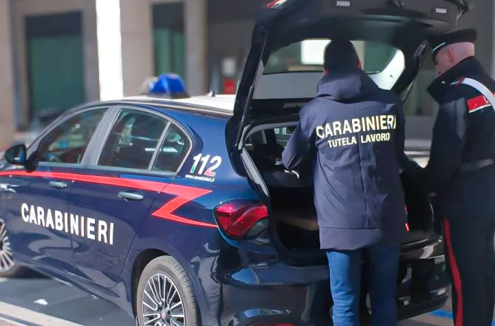 Carabinieri, uno con la giacca della Tutela lavoro, accanto a un'auto di servizio